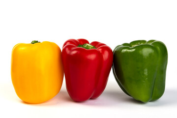 Yellow, red and green bell peppers on a white background
