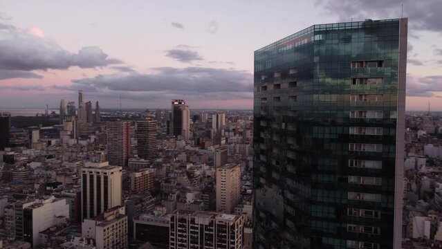 Drone shot over downtown of Buenos Aires with modern glass building in foreground during purple sunset at horizon - Argentina,South America