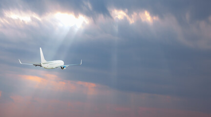 Airplane in the sky with sun rays at sunset