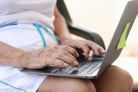 Hands of mature elderly woman are typing on laptop