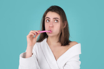 Young cheerful woman brushing teeth with toothbrush during morning hygiene procedures isolated background, facial funny portrait. Dental concept.