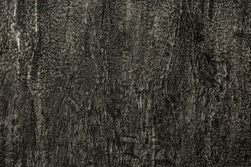Dark background of decorative plaster with abstract spots. Unusual black or gray wall texture with beautiful patterns, creative surface background. Finishing coating for building cladding.