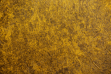 Golden wall with abstract spots as a background. Beautiful golden texture with patterns, decorative plaster. Modern bright wall painting in trendy shades, unusual spotted yellow and gold surface.