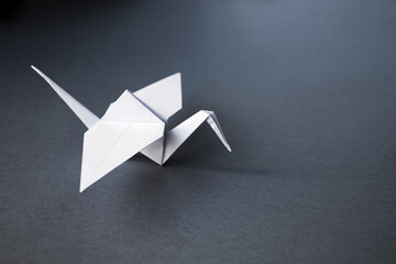 White paper crane origami isolated on a grey background