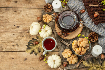 Autumn tea concept. Cookies with pumpkin puree, black tea in a glass teapot, fall decor