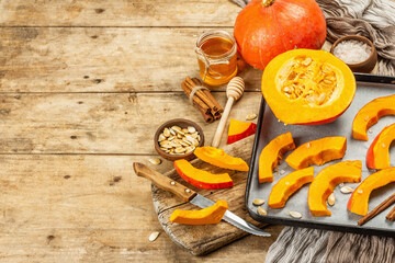 Traditional Autumn wooden background with Hokkaido pumpkin, honey, and spices ready for baking
