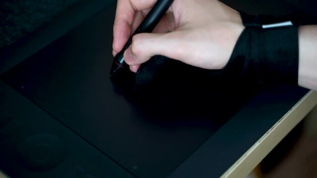 Close-up of hand drawing on a digital tablet with pen. Professional retoucher working on graphic tablet.
