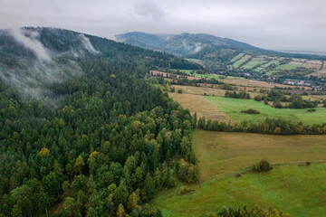 Obraz premium Aerial view of the foggy morning at the forest and green hills. 