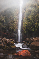 Fototapeta na wymiar In rainy weather, the majestic and well-known 25fontes waterfall rises in the mist and rain on the island of Madeira, Portugal. Discovering magical places in Europe