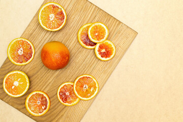 Blood Sicilian fresh oranges on wooden cutting board. Sliced ripe juicy citrus fruits on beige background. Top view,flatlay,copy space