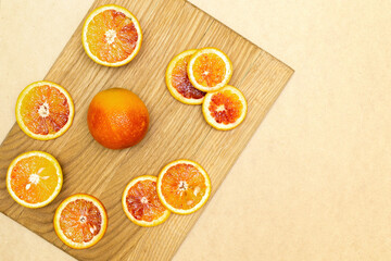 Blood Sicilian fresh oranges on wooden cutting board. Sliced ripe juicy citrus fruits on beige...