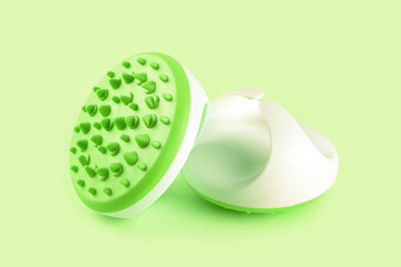 Hand massager with silicone spikes for anti-cellulite massage procedure isolated on green background. Massage brush tool for problem body zone, self-care, health care, body therapy.