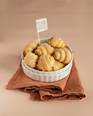 Pastry rolls. Mini cottage cheese croissants. Bagels with sugar in the white ceramic bowl on the coral linen kitchen towel