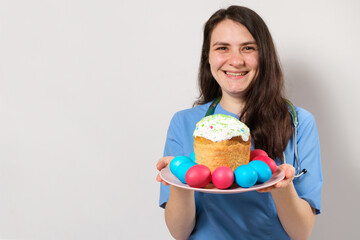 The doctor holds an Easter cake and smiles, a place for text. Medical Easter