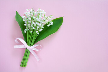 Bouquet of white lily of the valley flowers on a pink background