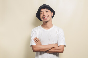 Fototapeta premium asian man wearing bright white t-shirt with black hat smiling cool on isolated background