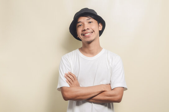 asian man wearing bright white t-shirt with black hat smiling cool on isolated background