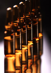 Six medical brown ampules on reflected surface in studio