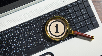 Magnifying glass with a Information symbol on the computer keyboard.