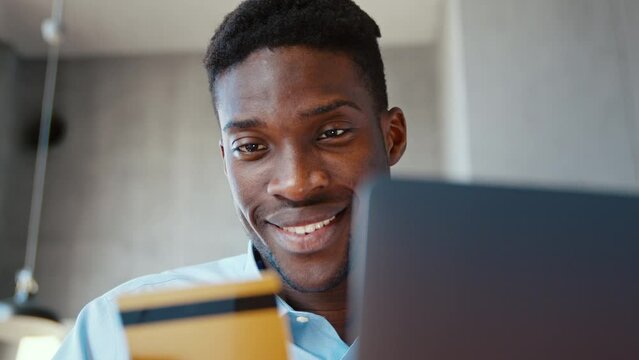 Smiling young man using laptop enter credit card numbers