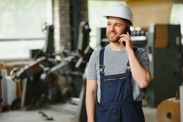 Management team, engineer, or foreman. Standing checking job information about industrial production management within the factory by phone. Teamwork concept