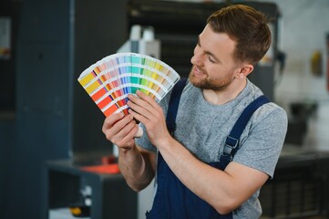 Man working in printing house with paper and paints