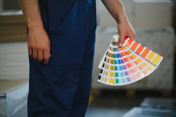 Funny portrait of typographer standing with color swatches at the printing manufacturing