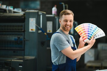 Man working in printing house with paper and paints