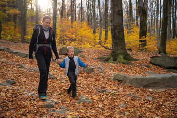 Mum and child are walking along the mountain hiking trail. Family spending time.