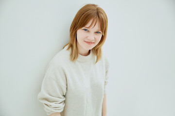 Portrait of young red haired cheerful girl smiling looking at camera over white background.