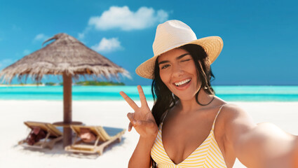 people, summer and swimwear concept - happy smiling woman in bikini and straw hat taking selfie and...