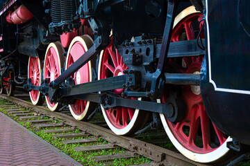 red wheels of an old steam locomotive on the rusty rails of the museum