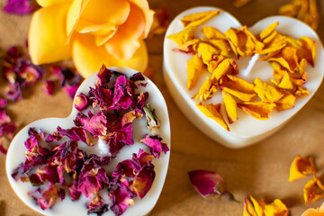 Herz Kerzen mit roten und gelben Rosenblüten. Ansicht von oben in Nahaufnahme