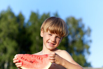 Happy young smiling boy eating watermelon in outdoor