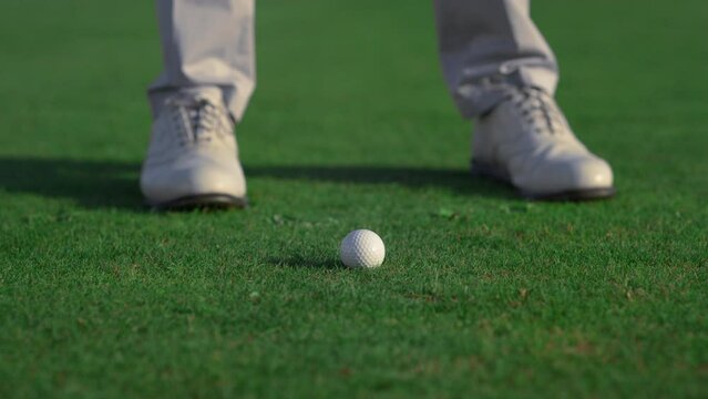 Golfer feet hitting ball on fairway course. Golf man swinging shot on training.