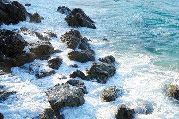 Obraz premium White bubble from sea water bounce with rocks on the beach in morning light. Beauty nature background.