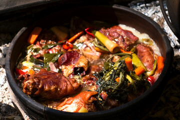 Serbian pork knuckle (svinjska kolenica) stewed under sać pot with potatoes and vegetables