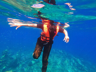Young man snorkeling scuba diving with life jacket at the Great Barrier Reef in the tropical.