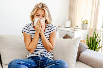 Young sick woman sneezing in tissue sweating from flu fever. Sick woman catch cold. Sneezing with...