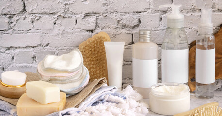 Fototapeta na wymiar Skin care cosmetics and bath accessories against white brick wall close up. Brand packaging mockup