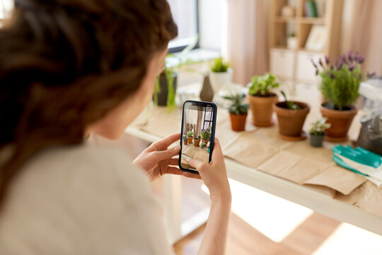 people, gardening and housework concept - close up of woman with smartphone photographing pot flowers at home