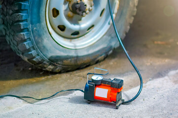 An automobile compressor in soft focus inflates a flat car tire. selective focus. Shot in backlight and sun glare.