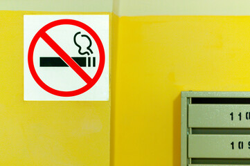 No smoking sign on yellow wall. Smoking ban in the entrances of residential buildings, prevention.