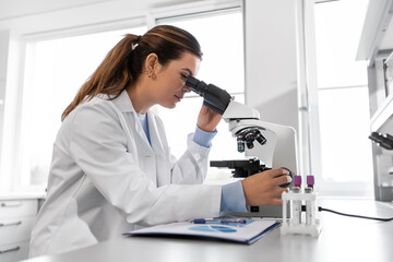 science research, work and people concept - female scientist with microscope working in laboratory