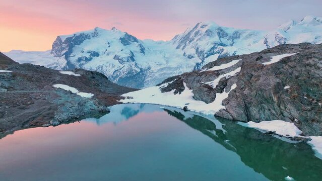 Swiss Alps at dawn, flying over a mountain lake in Switzerland near Gornergletcher and Monte Rosa, beautiful Swiss nature, alpine adventure, snow covered mountain range at sunrise