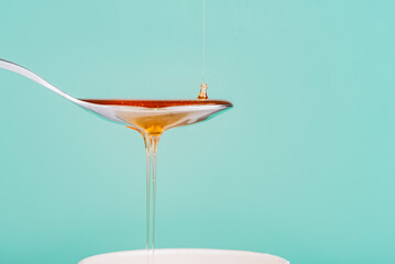 close up of honey being poured into a silver spoon, honey is a natural sweetener as a substitute...