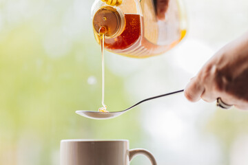 Pouring natural honey into spoon to put in to morning tea