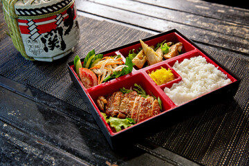 Teriyaki chicken bento with dumplings and salad in the traditional Japanese ramen restaurant, with...