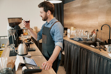 Thoughtful barista appraisingly looks at a glass of filter coffee