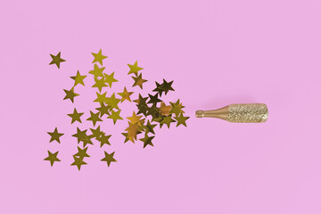 Golden star confetti splashing out of Champagne bottle on pink background